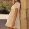 Mini sukienka babydoll w stylu regencyjnym z satyny w kolorze kości słoniowej i koronki broderie anglaise Mini sukienka babydoll w stylu regencyjnym z satyny w kolorze kości słoniowej i koronki broderie anglaise