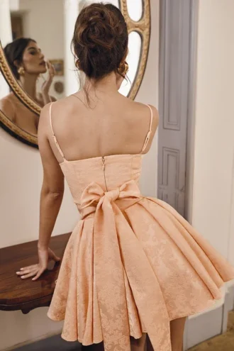 Mini suknia wieczorowa z kokardą Rosalinda w kolorze brzoskwiniowym z żakardowym wzorem Mini suknia wieczorowa z kokardą Rosalinda w kolorze brzoskwiniowym z żakardowym wzorem